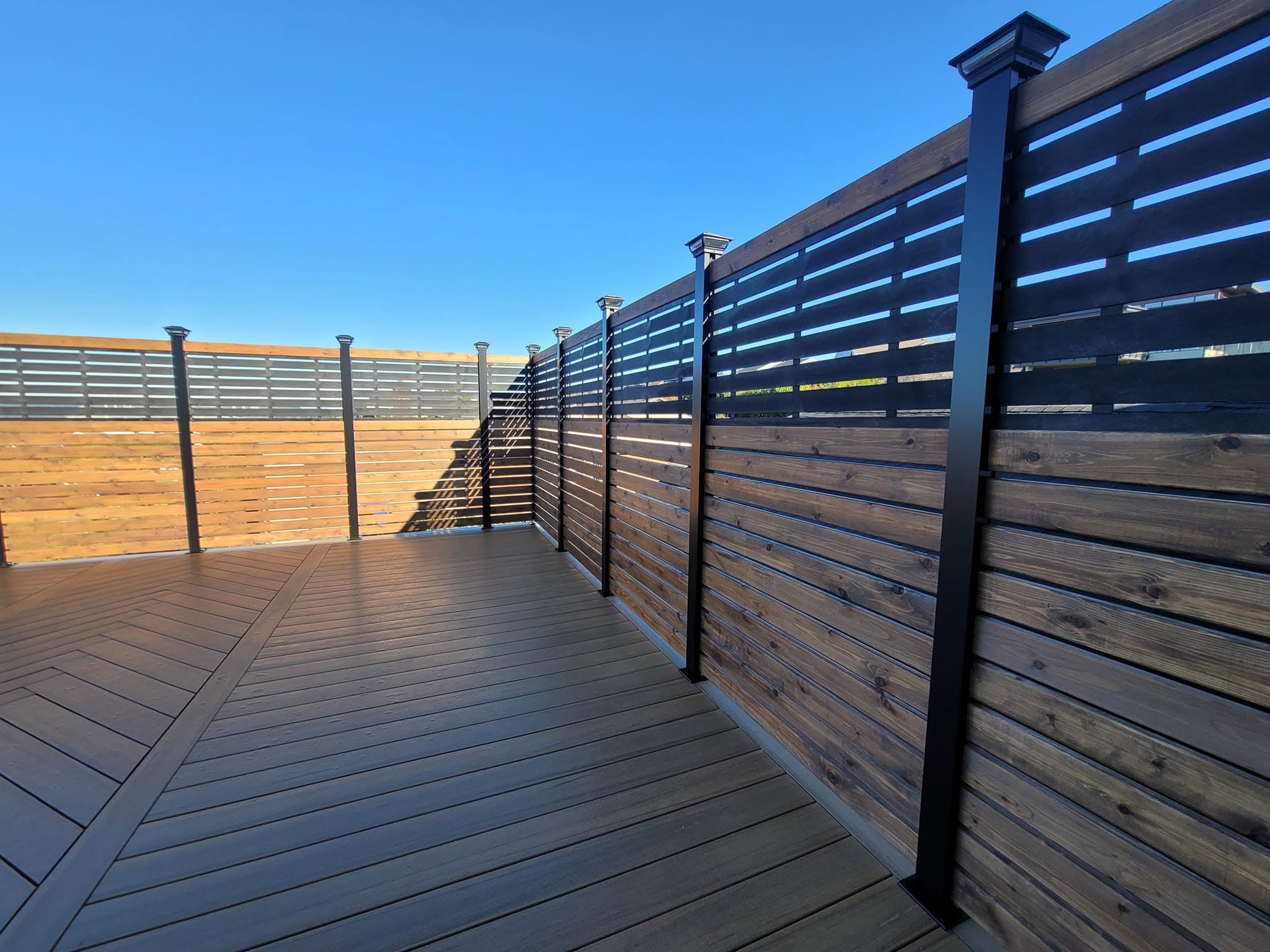 Horizontal cedar and black aluminum privacy screen with solar post-cap lights