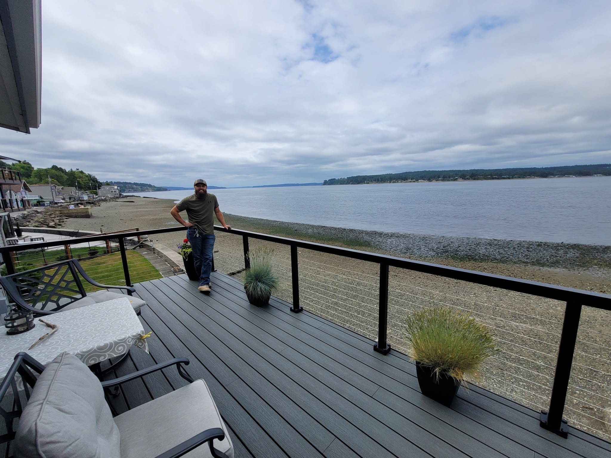 Waterfront composite deck with black cable railing and Puget Sound views